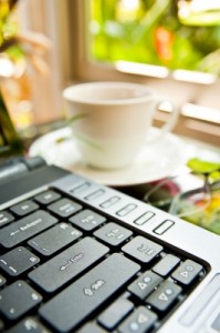 Laptop keyboard with ceramic coffee cup in the background