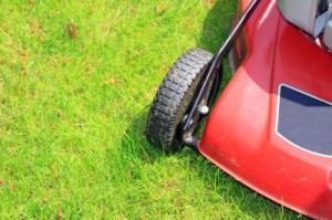 Corner of red lawnmower on green grass