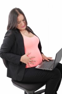 Pregnant woman having some contractions holding a laptop
