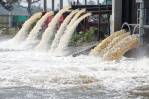 Brown water flowing from raised pipes into more water