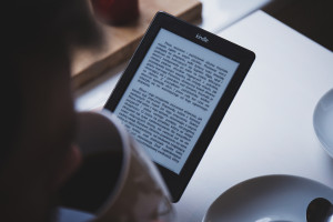 Person drinking coffee and reading Kindle by free stocks.org