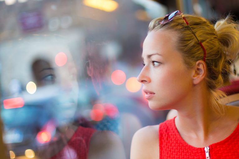 Thoughtful lady riding on a tram and looking out the window.