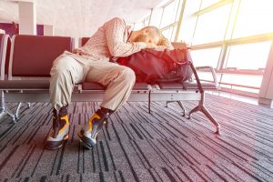 Man sleeping, head on bag, in airport