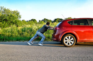 Man and woman pushing a broken car