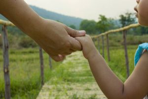 Parent holds the hand of a little child green background, soft focus High resolution image gallery.